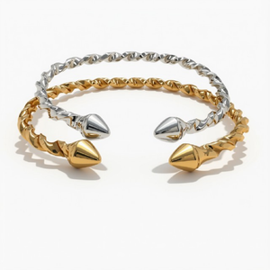 Twisted open cuff bracelet featuring textured gold and silver metal bands with polished conical end caps, shown on a plain white background.