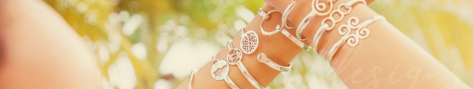 Two arms wearing silver ib designs bracelets and bangles